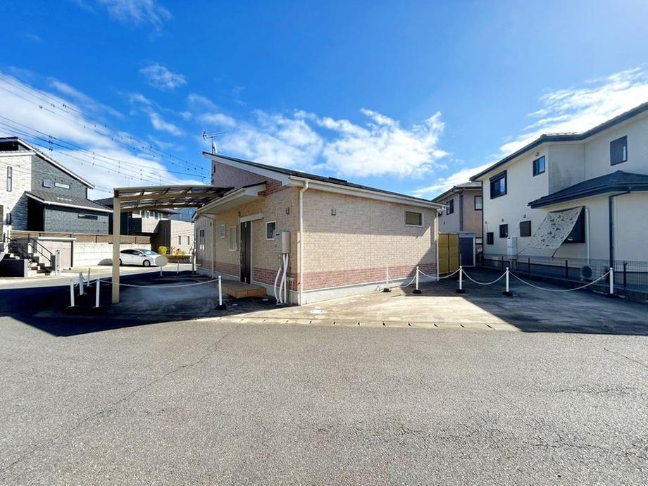 敷地内にカーポート付き駐車スペースがあり、平屋建ての外観が特徴的です。