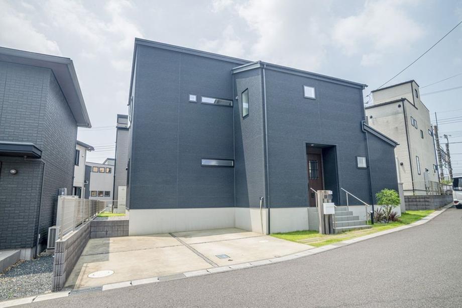 ダークトーンの外観が特徴的な戸建住宅。駐車スペースが広く、玄関までのアプローチもゆとりがあります。