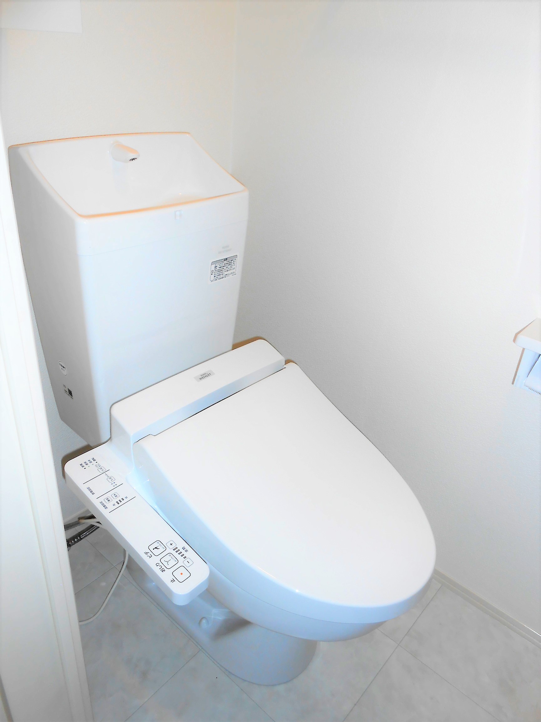 トイレ　ウォシュレット付き。後ろには収納棚があります。