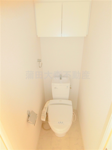 トイレ　吊戸棚と温水洗浄便座付きのトイレ