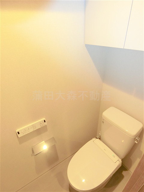 トイレ　吊戸棚と温水洗浄便座付きのトイレ