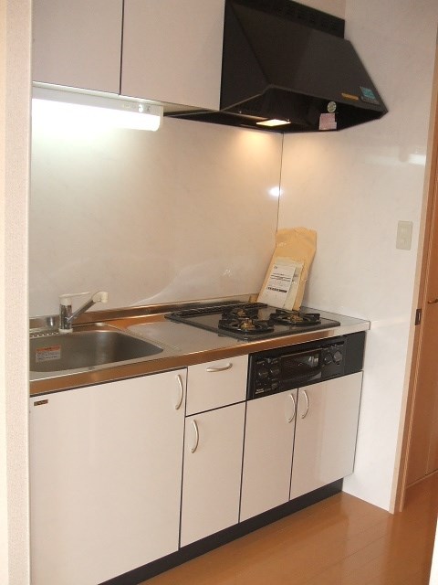 キッチン　３口ガスコンロのシステムキッチン。落ち着いた木目調のデザイン