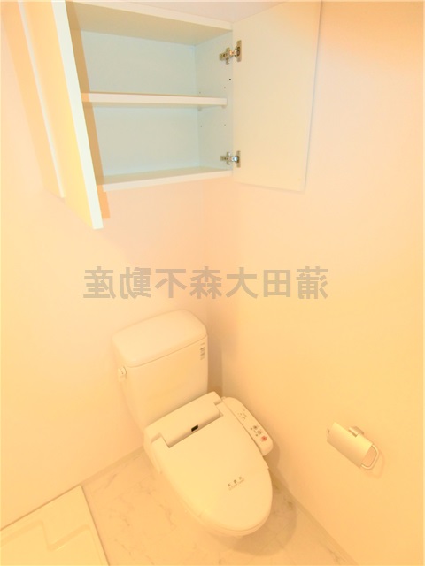 トイレ　吊戸棚と温水洗浄便座付きのトイレ