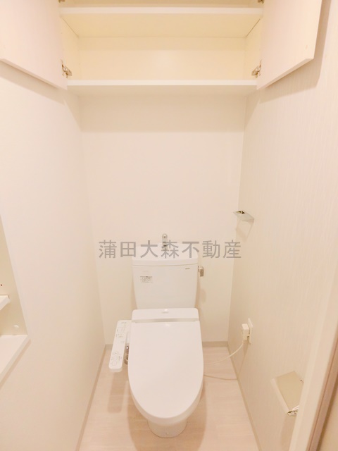 トイレ　棚と温水洗浄便座付きのトイレ