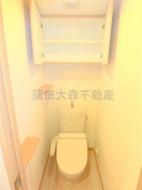 トイレ　吊り戸棚と温水洗浄便座付きのトイレ