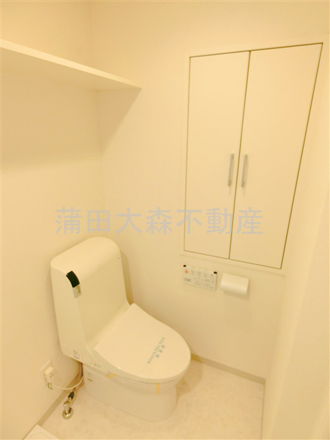 トイレ　棚と温水洗浄便座付きのトイレ