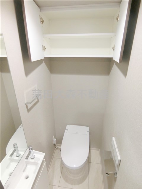 トイレ　吊戸棚と温水洗浄便座付きのトイレ