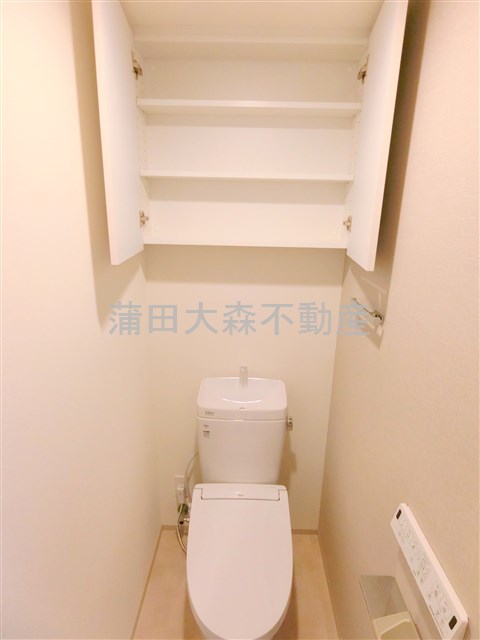 トイレ　吊戸棚と温水洗浄便座付きのトイレ