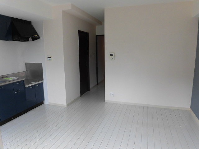 居室・リビング　白い壁と床に青いキッチンがおしゃれなリビングです。