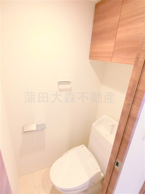 トイレ　吊戸棚と温水洗浄便座付きのトイレ
