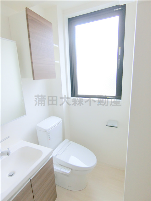 トイレ　窓と吊戸棚+温水洗浄便座付きのトイレ