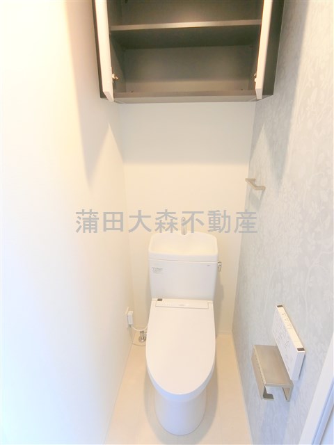 トイレ　吊戸棚と温水洗浄便座付きのトイレ