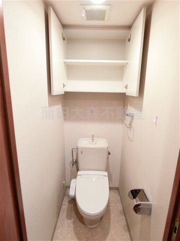 トイレ　吊戸棚と温水洗浄便座付きのトイレ