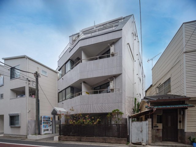 建物外観　白タイル張りの外観。２階右側のバルコニーが203号室です。