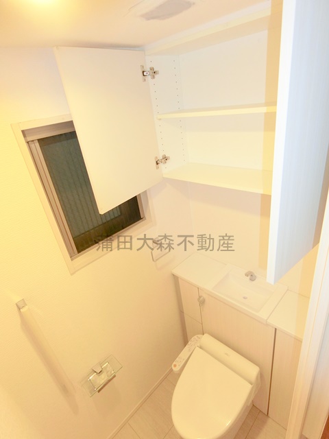 トイレ　吊戸棚と窓、温水洗浄便座付きのトイレ