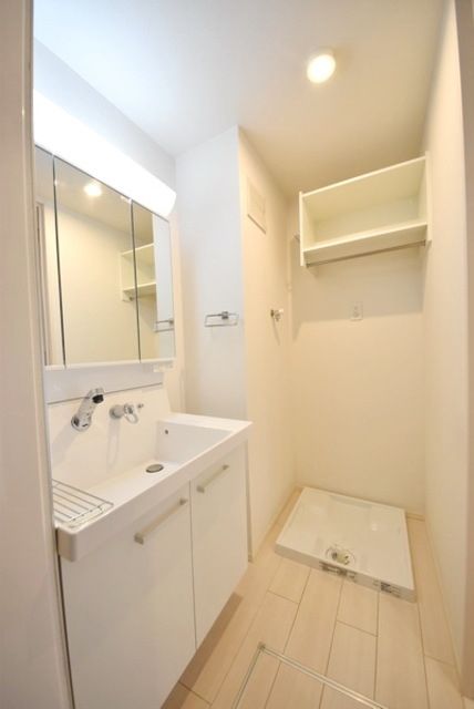 洗面設備　棚のある洗濯機置き場とシャワーホース付きの洗面台