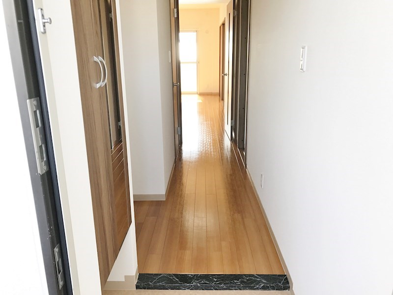 玄関　玄関を開けるとバルコニー側からの光が差し込んだリビングが迎え