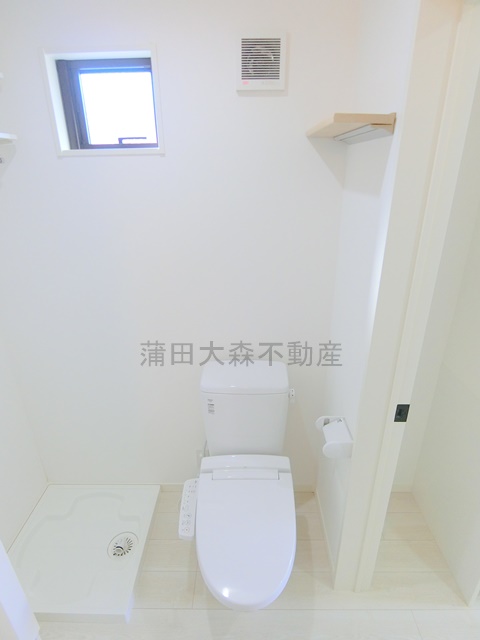 トイレ　棚と窓、温水洗浄便座付きのトイレ