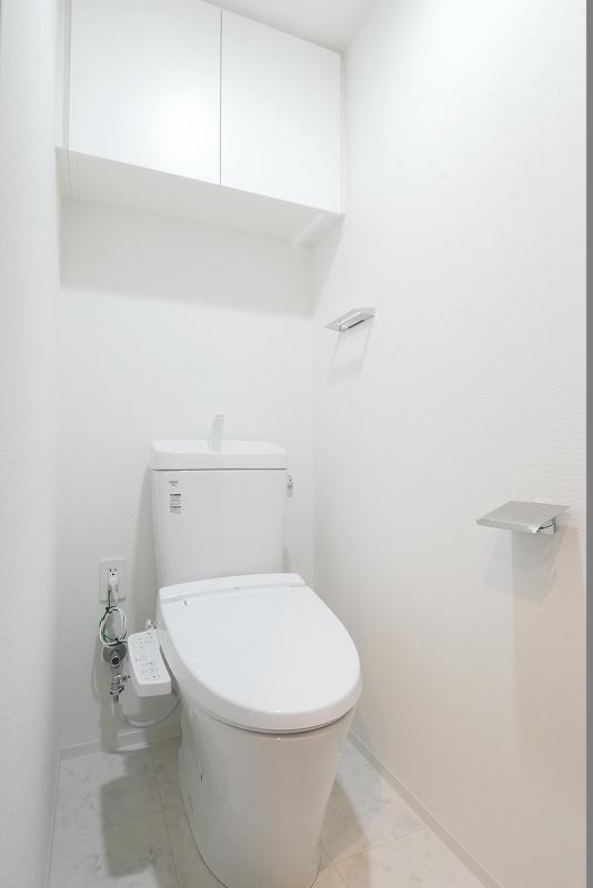 トイレ　吊戸棚と温水洗浄便座付きのトイレ
