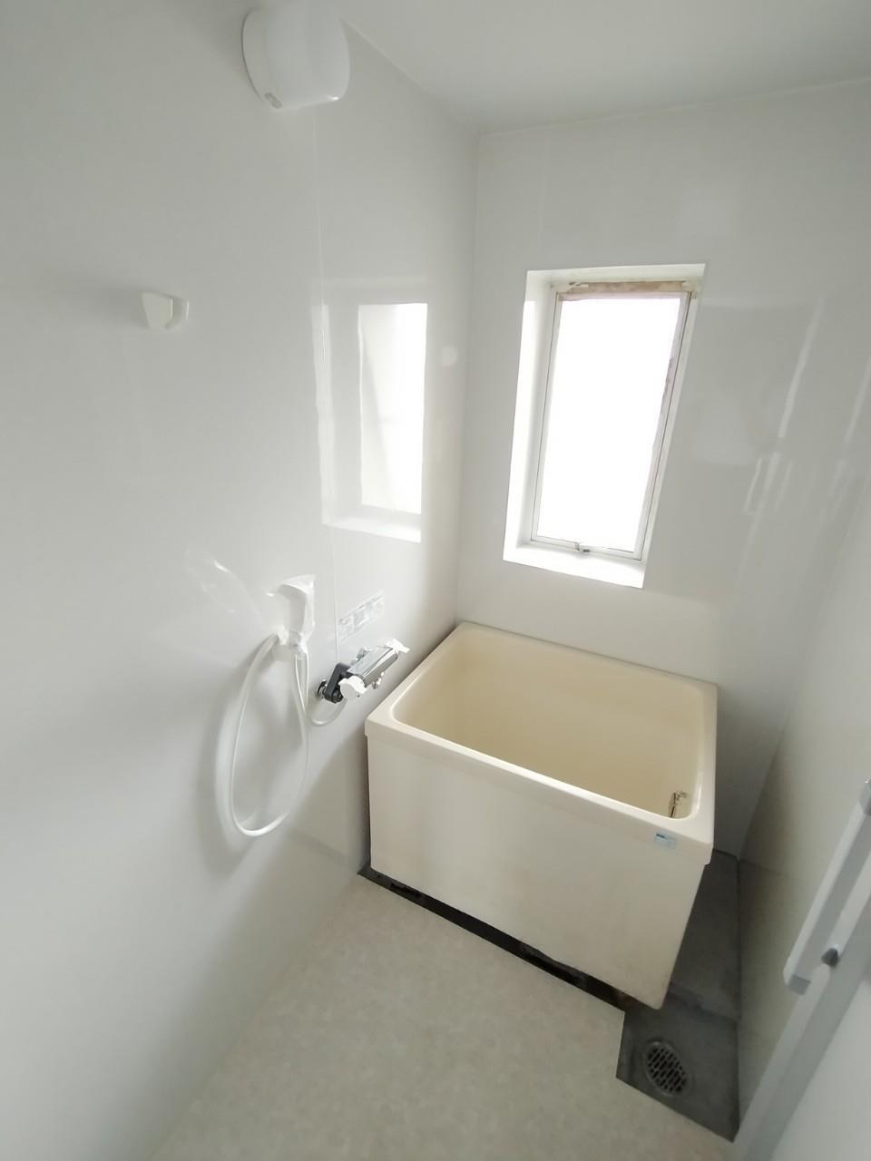 バス・シャワールーム　清潔感のある浴室。窓付きで換気にも有利。全面パネルリフォーム