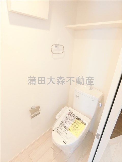 トイレ　上部棚と温水洗浄便座付きのトイレ