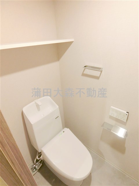 トイレ　棚と温水洗浄便座付きのトイレ