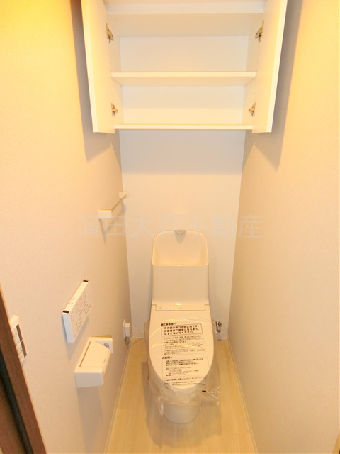 トイレ　吊戸棚と温水洗浄便座付きのトイレ