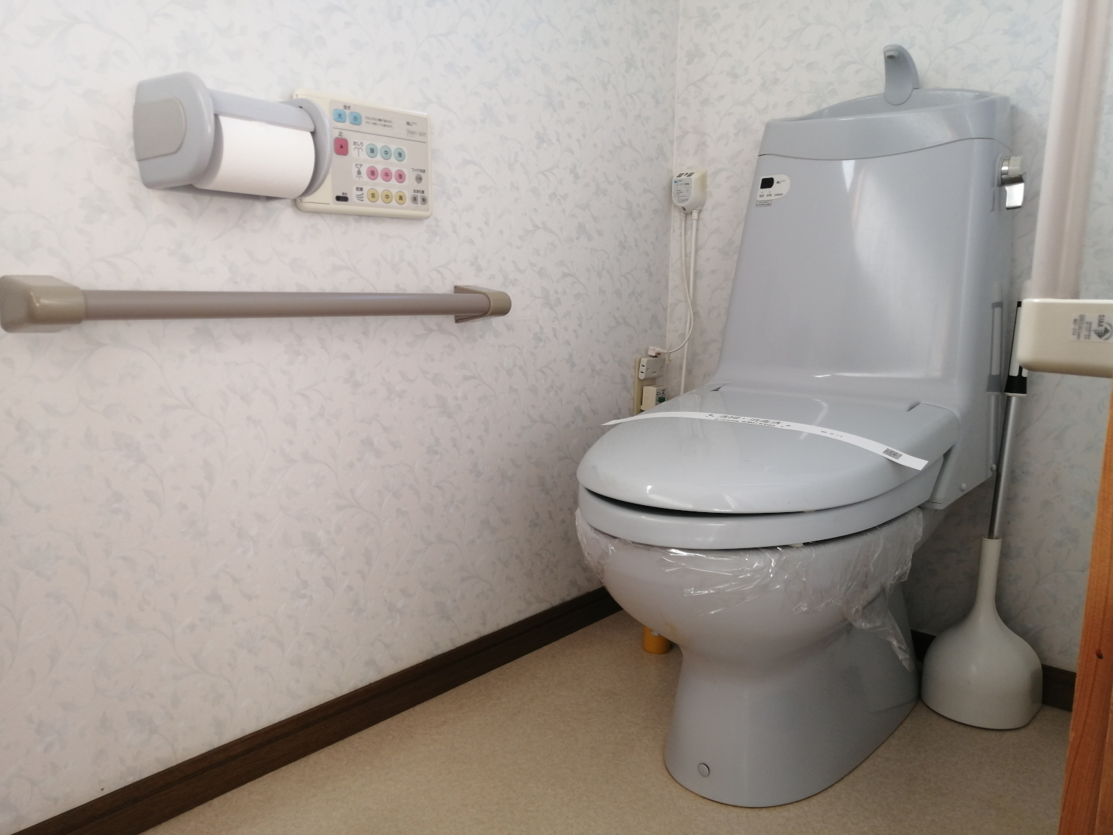 トイレ　立ち座りをサポートする手すり付き。温水洗浄便座。