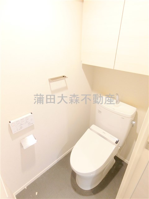トイレ　吊戸棚と温水洗浄便座付きのトイレ