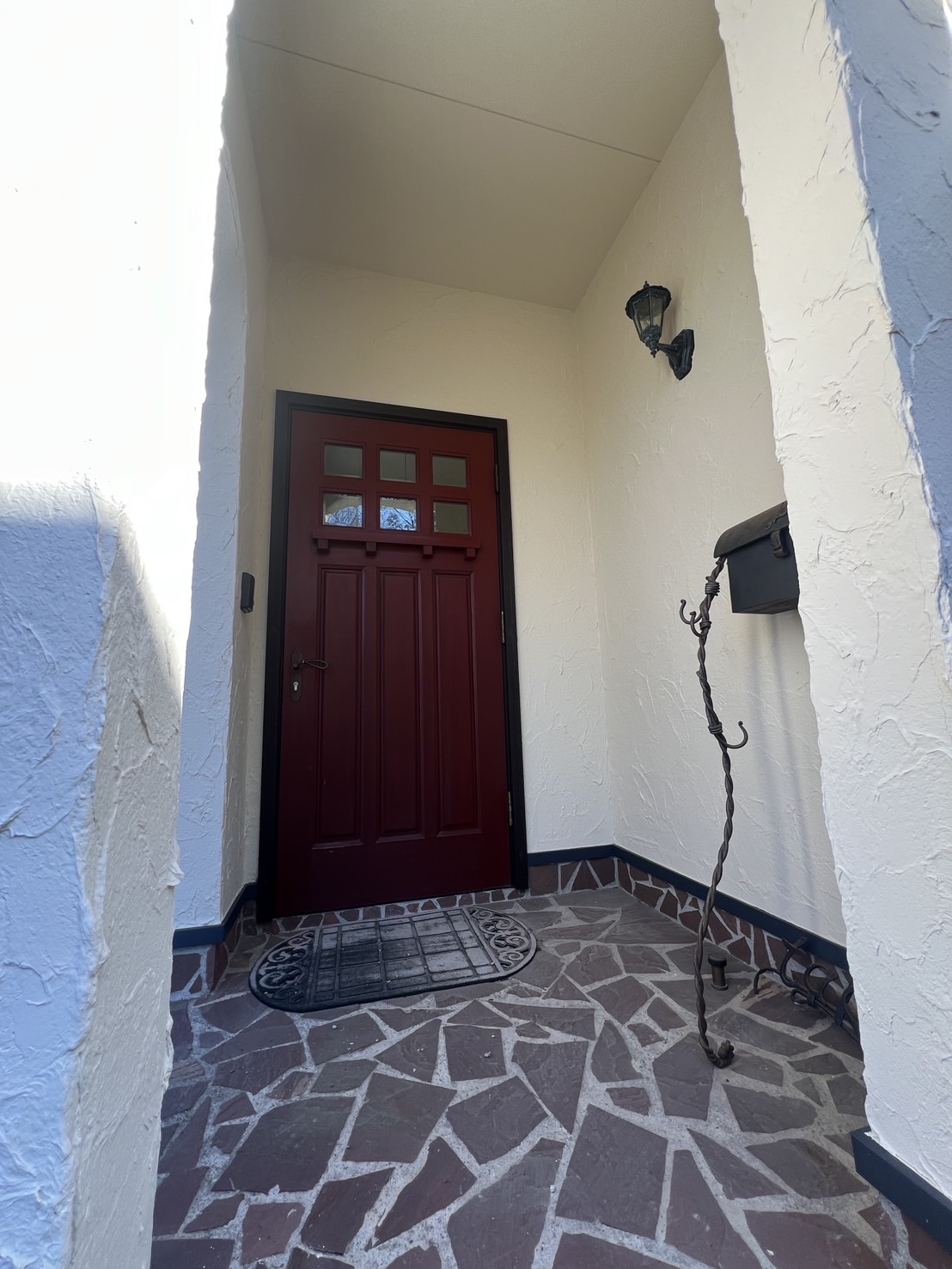 玄関　赤いドア　割石の床タイル　塗り壁