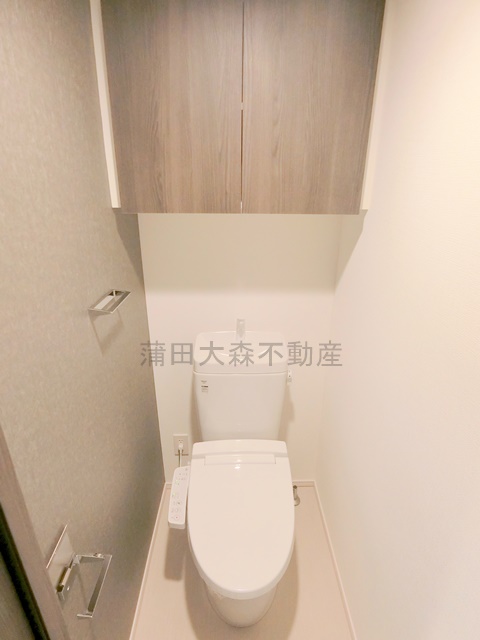トイレ　吊戸棚と温水洗浄便座付きのトイレ