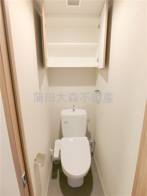 トイレ　吊戸棚と温水洗浄便座付きのトイレ