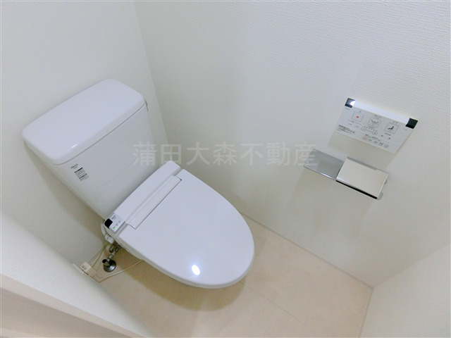 トイレ　吊り戸棚と温水洗浄便座付きのトイレ