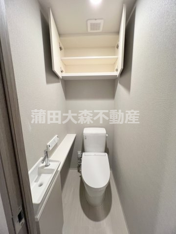 トイレ　吊戸棚と手洗い、温水洗浄便座付きのトイレ