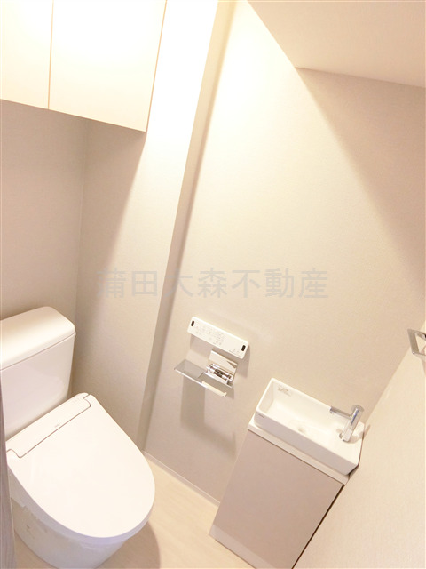 トイレ　吊戸棚と温水洗浄便座付きのトイレ