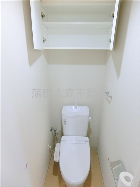トイレ　吊戸棚と温水洗浄便座付きのトイレ