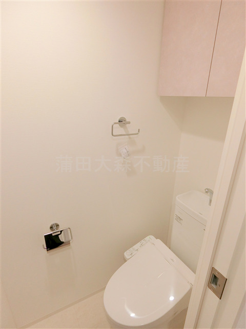トイレ　吊戸棚と温水洗浄便座付きのトイレ