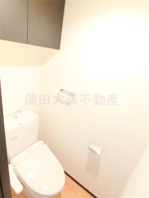 トイレ　吊戸棚と温水洗浄便座付きのトイレ