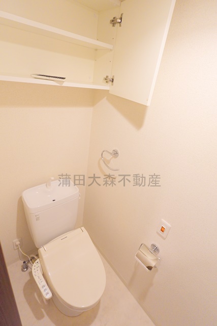 トイレ　吊戸棚と温水洗浄便座付きのトイレ