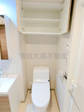 トイレ　吊戸棚と温水洗浄便座付きのトイレ