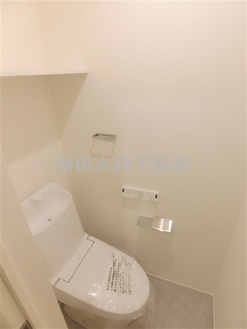 トイレ　棚と温水洗浄便座付きのトイレ