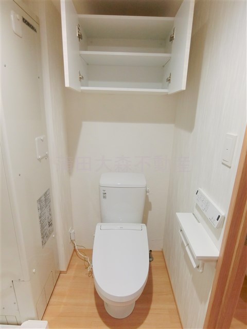 トイレ　吊り戸棚と温水洗浄便座付きのトイレ