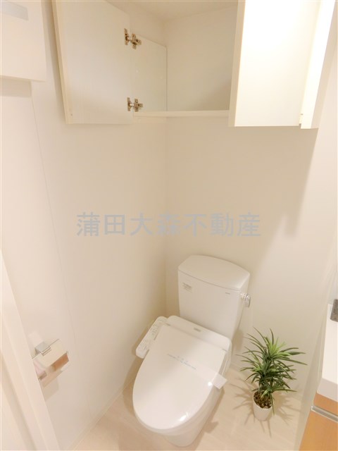 トイレ　吊り戸棚と温水洗浄便座付きのトイレ