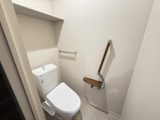 トイレ　シャワー式を採用　手摺と収納棚も備えます