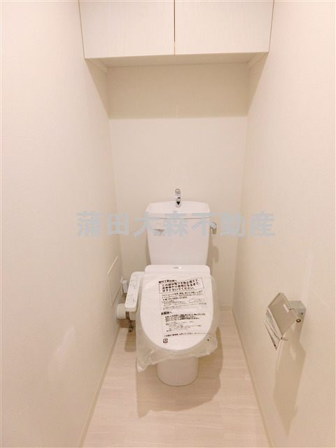 トイレ　吊り戸棚と温水洗浄便座付きのトイレ