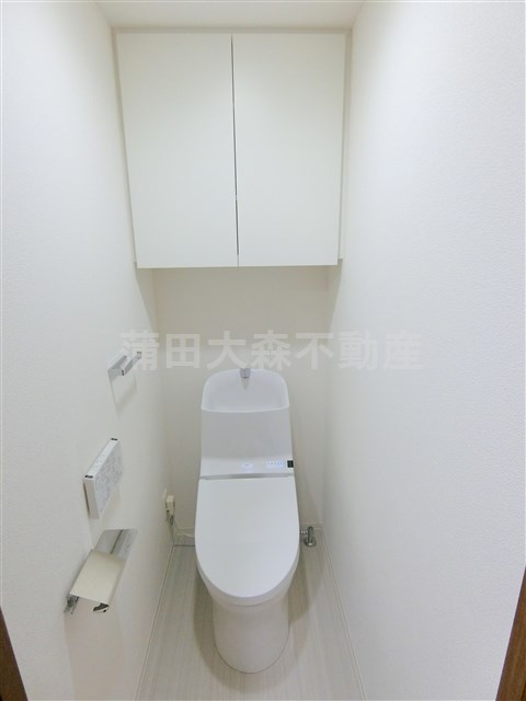 トイレ　吊戸棚と温水洗浄便座付きのトイレ