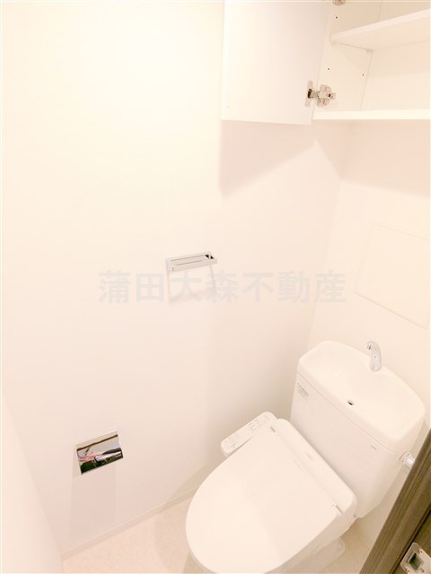 トイレ　吊戸棚と温水洗浄便座付きのトイレ