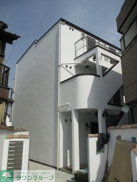 建物外観　お洒落なアプローチの先に建つ白塗りのアパート。