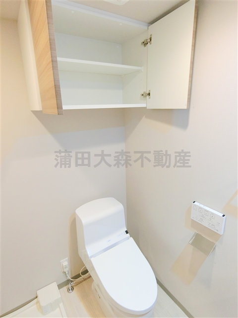 トイレ　吊戸棚と温水洗浄便座付きのトイレ