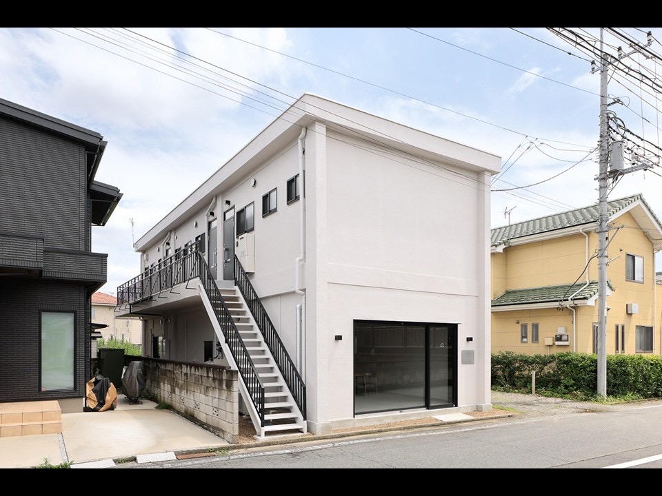 建物外観　やさしい白の壁と黒手すりが映える、端正な佇まい
